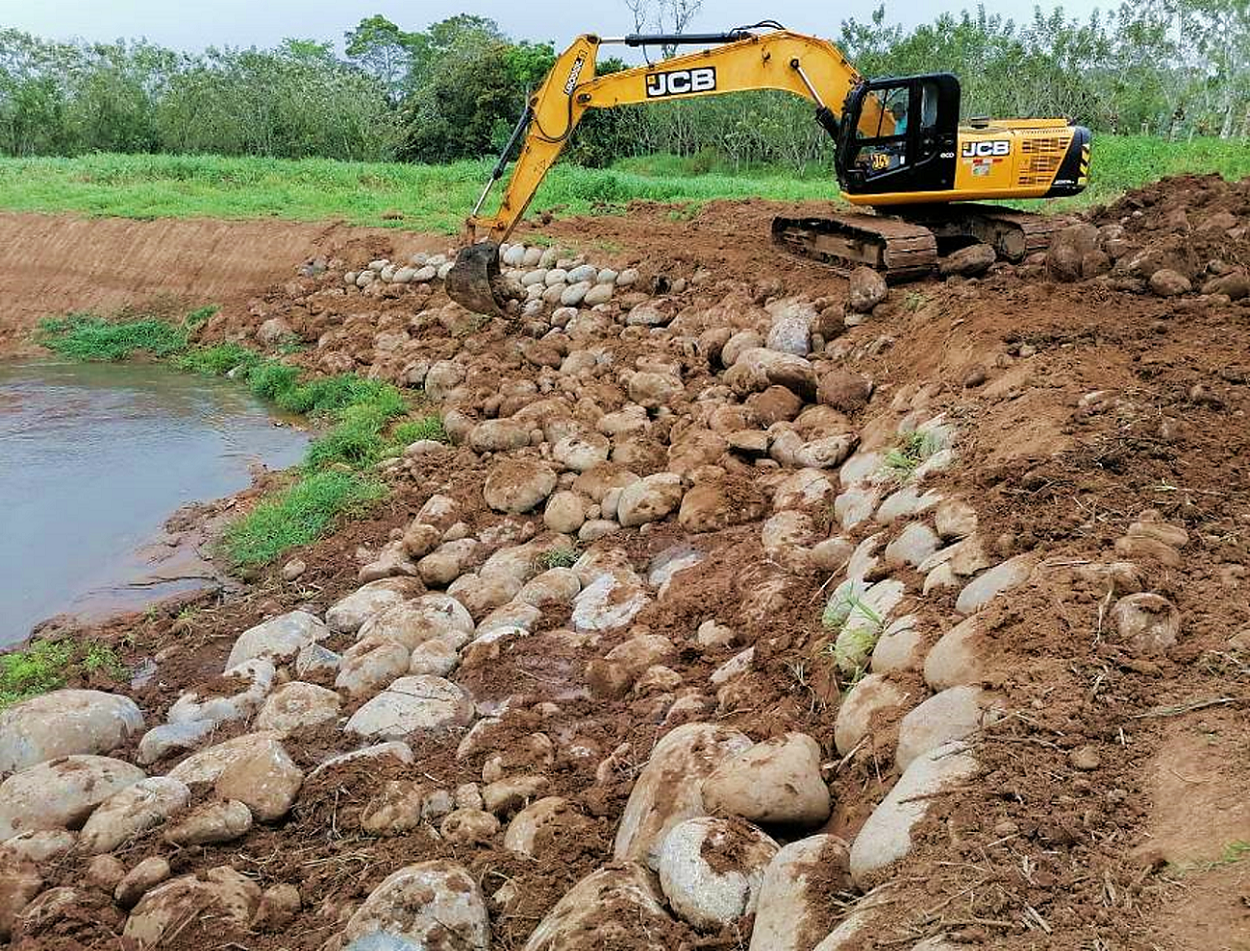 Una pala excavadora colocando un enrocado al margen de un río